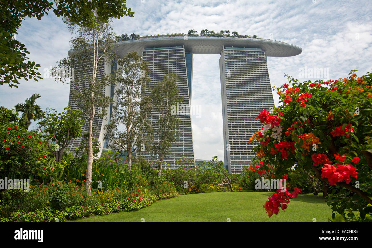 Il Marina Bay Sands casino resort, moderno edificio multipiano in Singapore, salendo in cielo accanto a variopinti giardini floreali Foto Stock