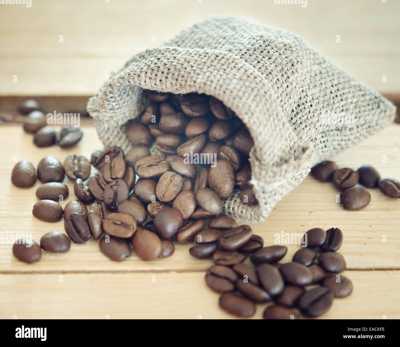 I chicchi di caffè in un sacco di tela su sfondo di legno Foto Stock