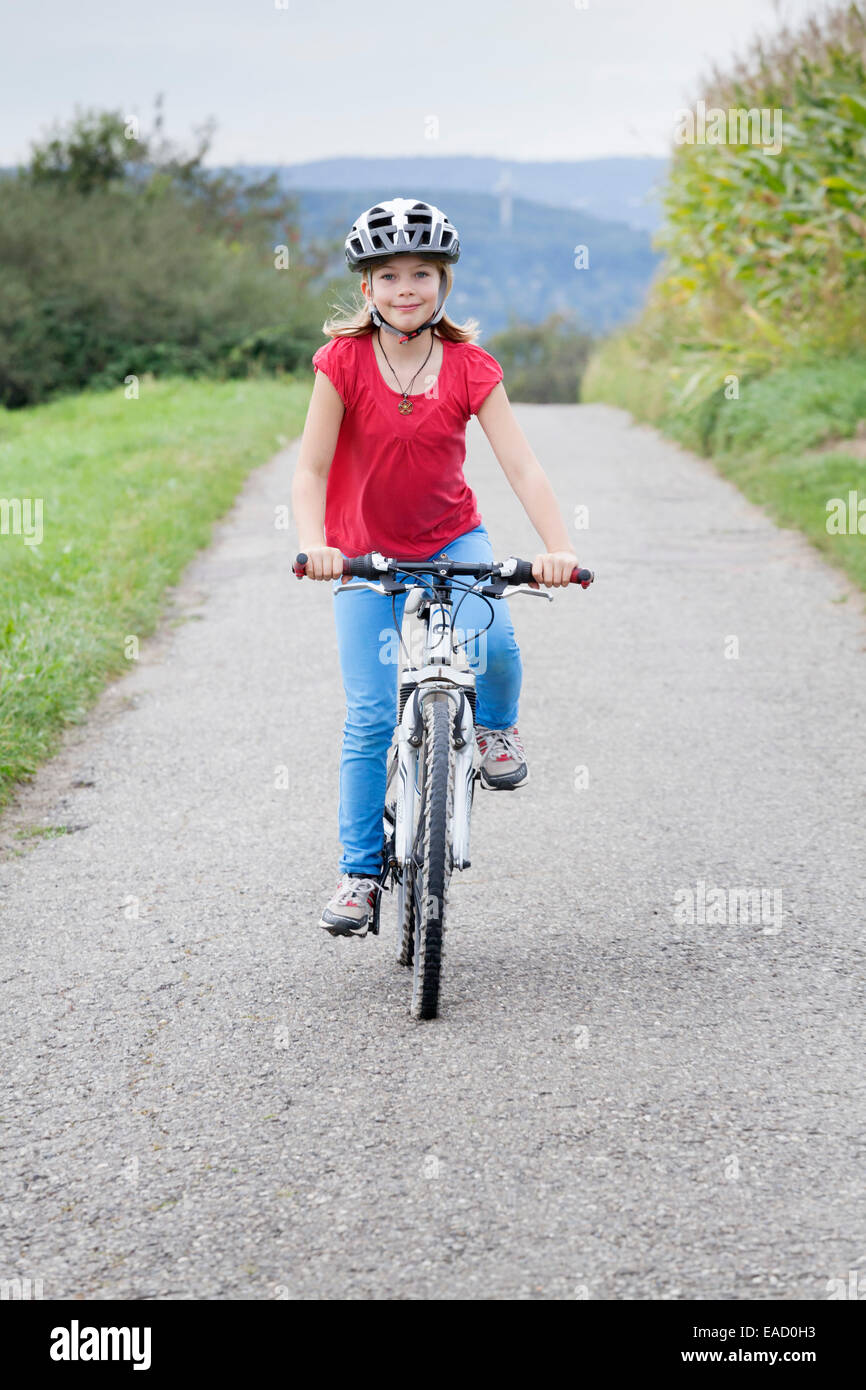 Ragazza 9 anni, in sella ad una bicicletta che indossa un casco Foto Stock