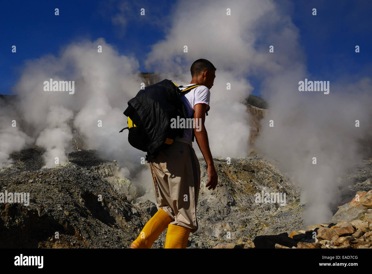 Un uomo che cammina su un sentiero di montagna, in uno sfondo del cratere vulcanico del vulcano Papandayan a Garut, Giava Occidentale, Indonesia. Foto Stock