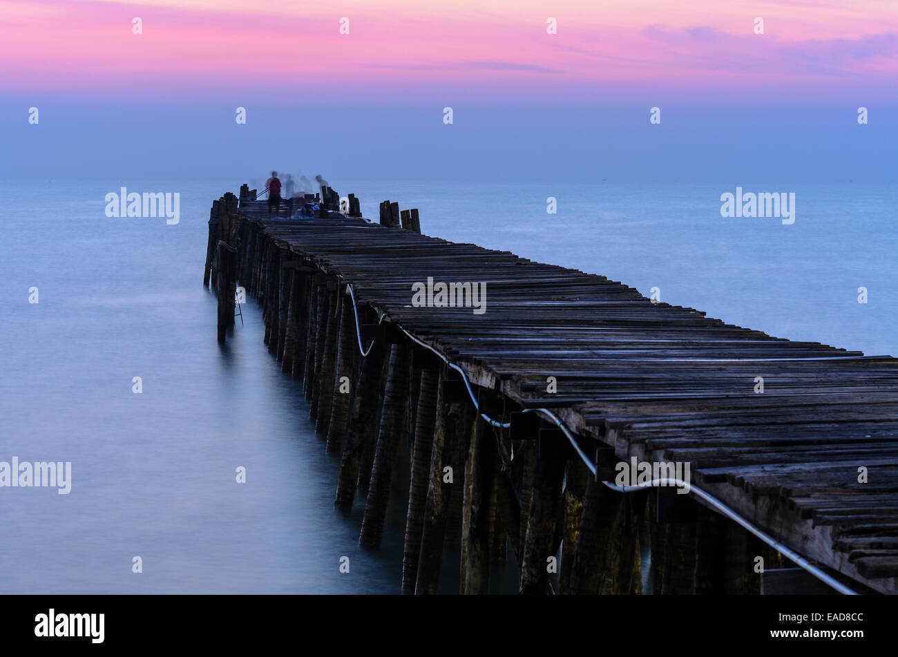 Silhouette pescatore sul vecchio ponte di legno e il mare a sunrise in zone rurali della Thailandia. Foto Stock