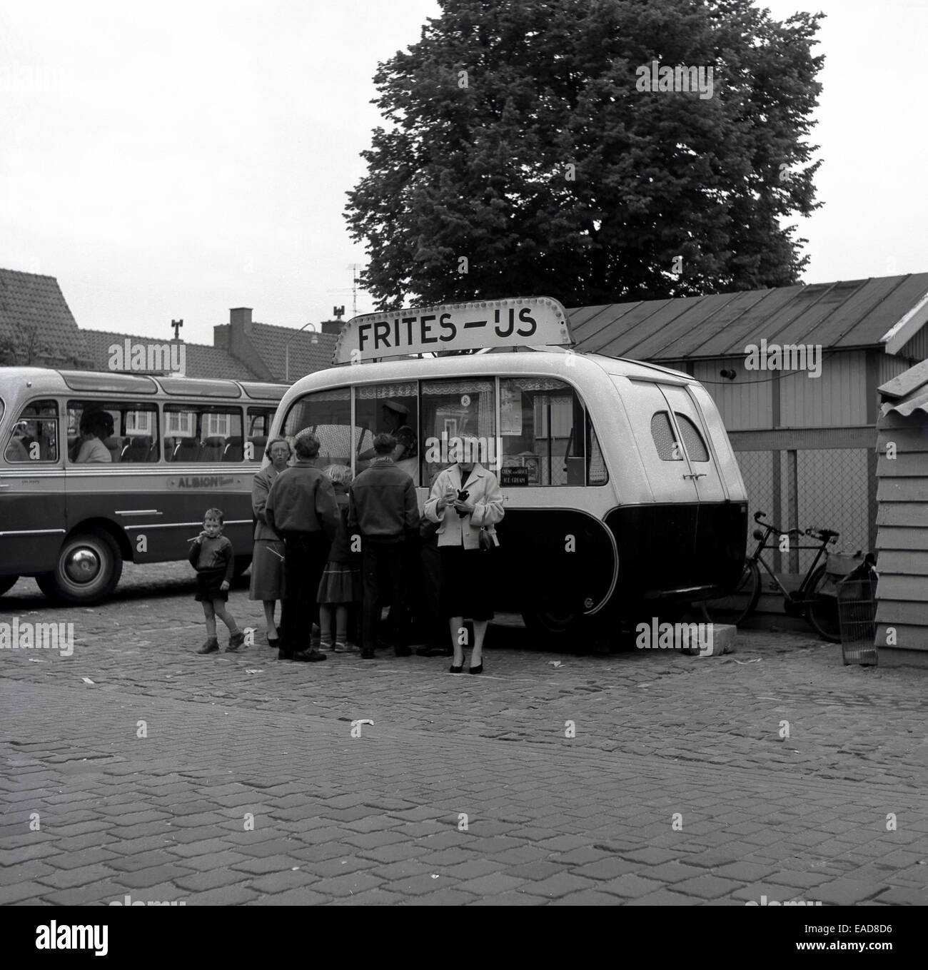 Anni sessanta foto storiche che mostra le persone al di fuori di stile continentale "cancelleria frites' kiosk o van con i clienti, Belgio. Foto Stock