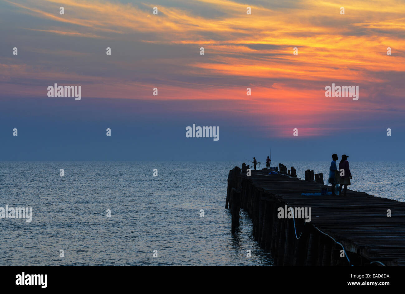 Silhouette pescatore sul vecchio ponte di legno e il mare a sunrise in zone rurali della Thailandia. Foto Stock