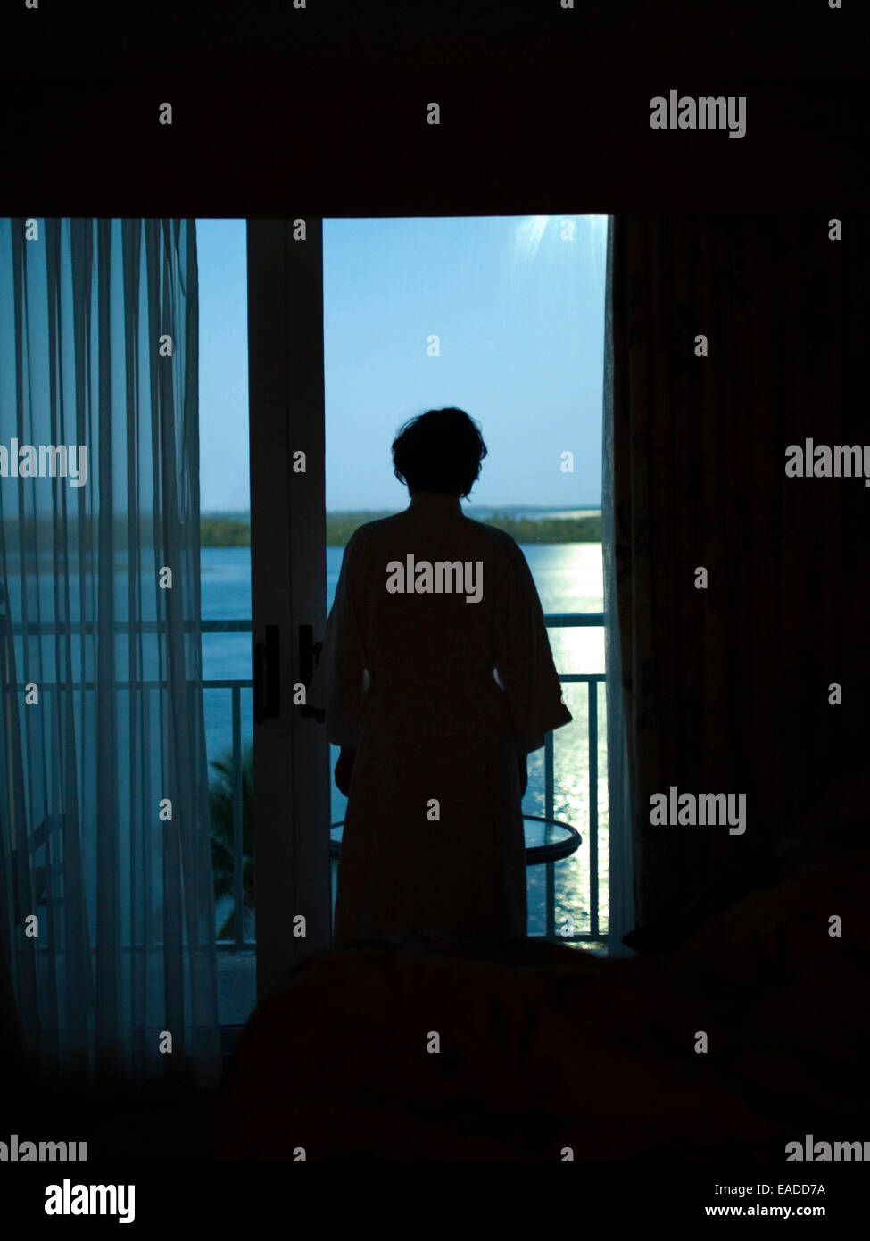 Donna dalla finestra di hotel all'alba Foto Stock