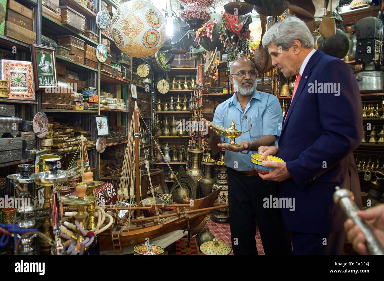 Muscat Oman. 10 Novembre, 2014. Il Segretario di Stato americano John Kerry esplora un negozio di artigianato come il negoziante offre una lampada ad olio durante una visita al souk Muttrah Novembre 10, 2014 in Muscat Oman. Kerry è in Oman per la P5+1 negoziati con l'Iran circa il futuro del suo programma nucleare. © Planetpix/Alamy Live News Foto Stock