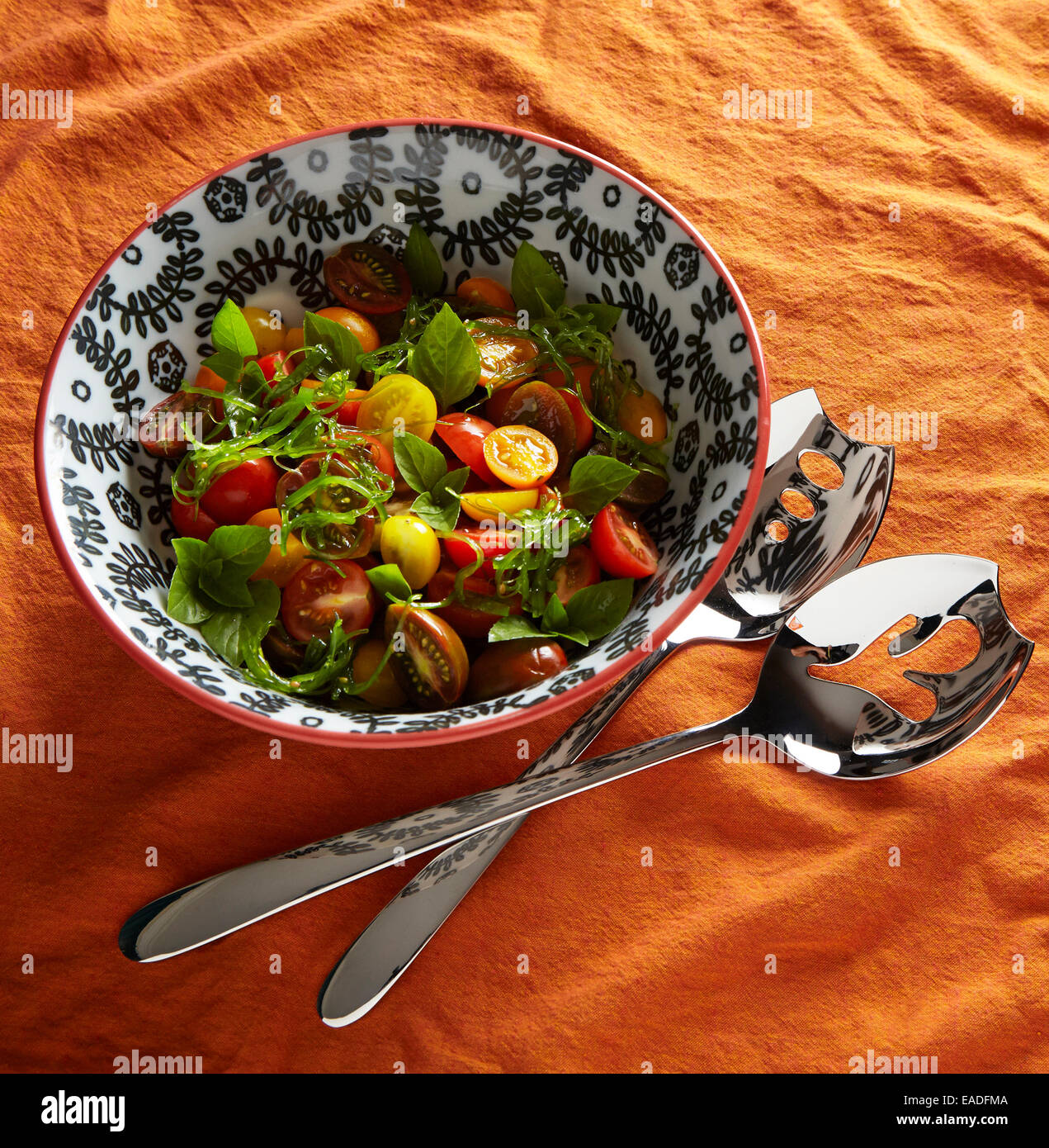 Mescolato al pomodoro, basilico e insalata di alghe marine su un arancio tovaglia cibo in un bianco e nero ciotola Foto Stock