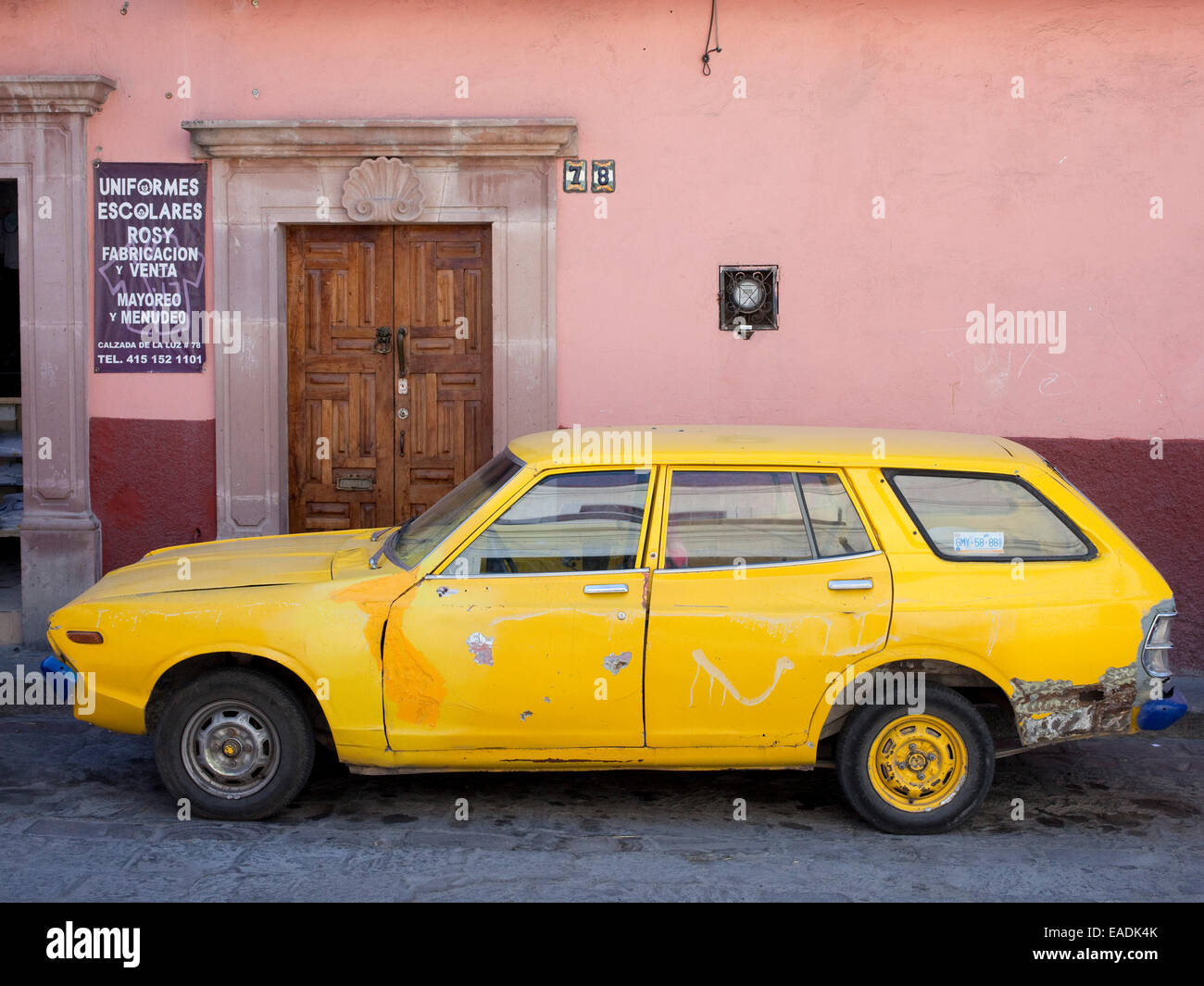 Vecchio giallo auto sulla strada di ciottoli nel villaggio messicano Foto Stock