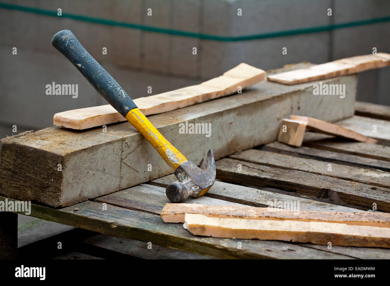 Dettaglio del martello in appoggio su un pezzo di calcestruzzo con residui di legno su un sito di costruzione Foto Stock