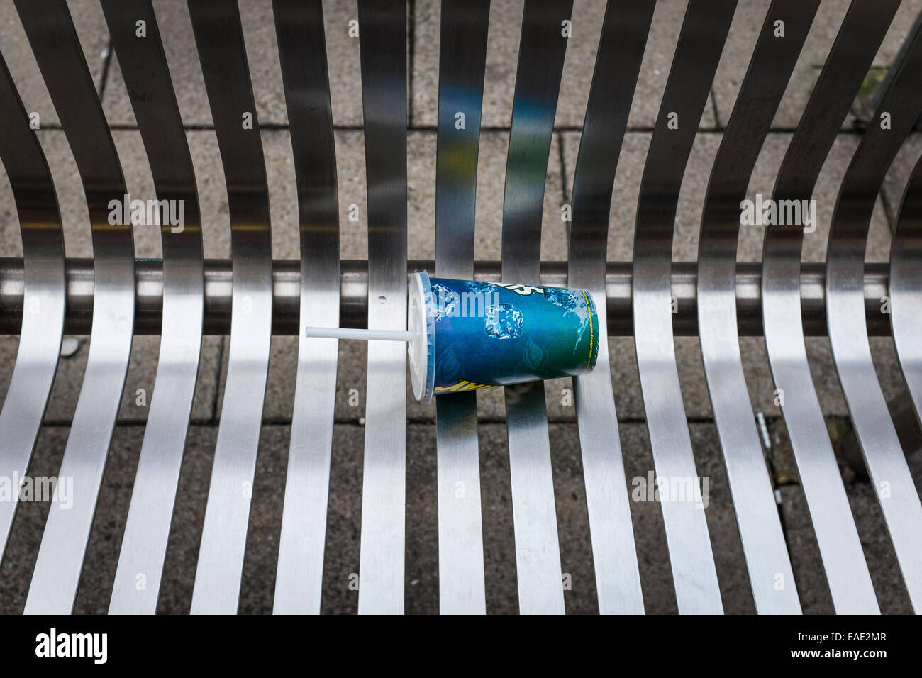 Vuoto di carta monouso tazza con tappo e paglia, giacente su un materiale metallico quale acciaio inossidabile al di fuori del banco. Foto Stock