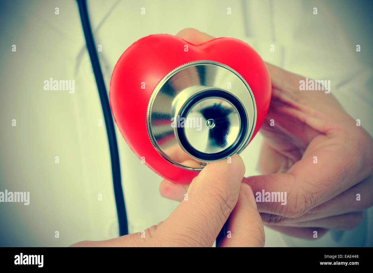 Un medico auscultating un cuore rosso con uno stetoscopio, con un effetto retrò Foto Stock