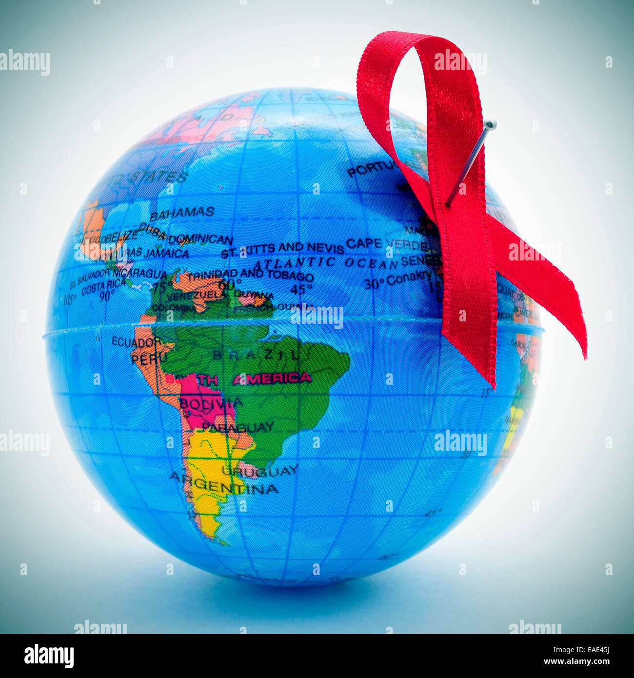 Una consapevolezza rosso nastro su un globo terrestre raffigurante l' idea della lotta mondiale contro l AIDS Foto Stock