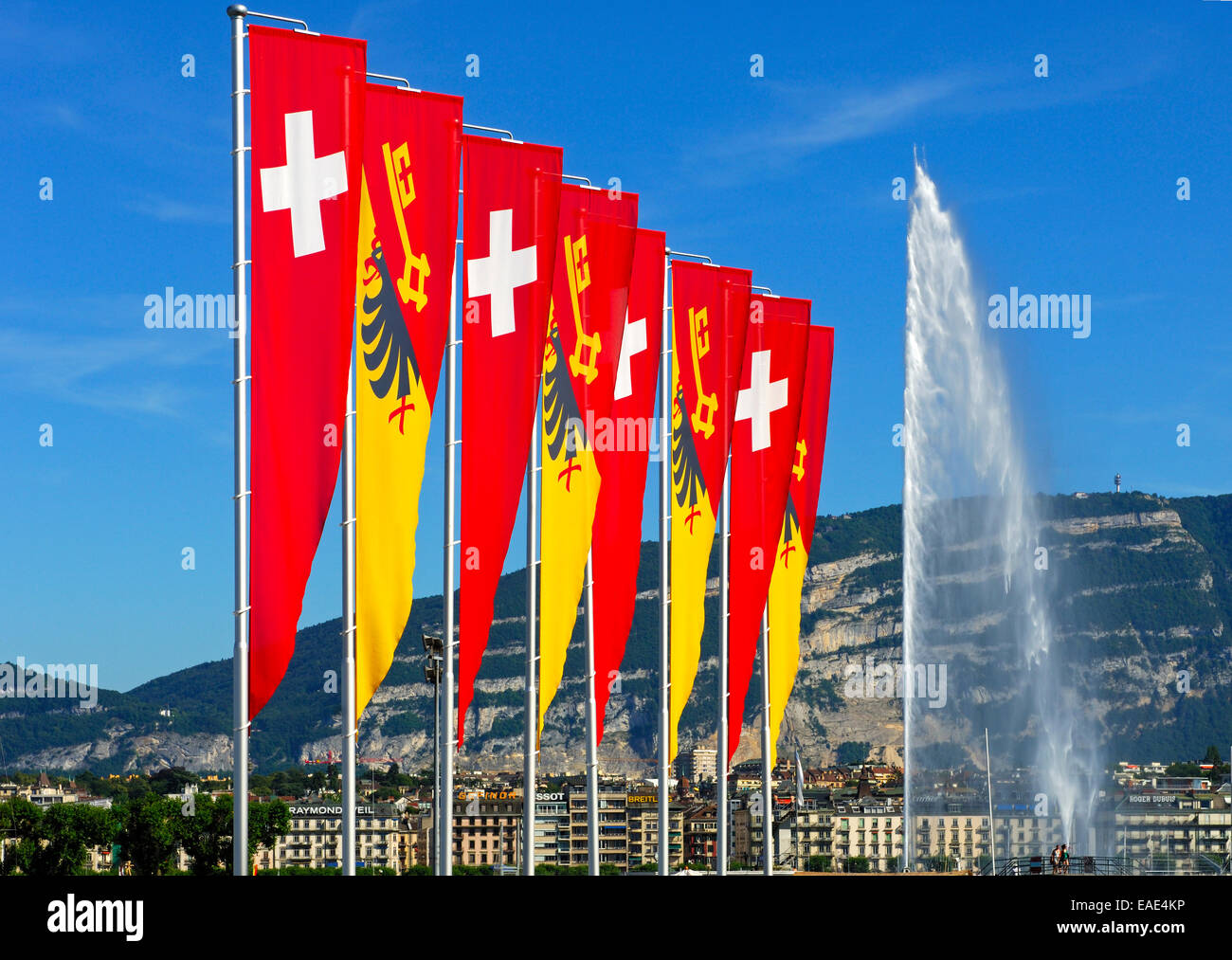 Le bandiere della Confederazione e del Cantone di Ginevra sulla passeggiata del lago di Ginevra con la fontana Jet d'Eau e il Foto Stock