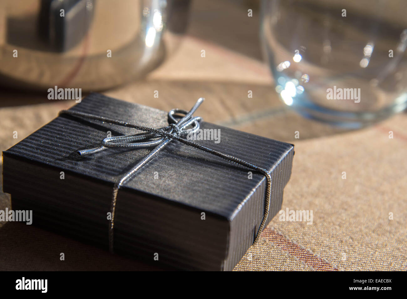 Piccoli gioielli nero confezione regalo con un arco di argento nella luce del sole di mattina Foto Stock