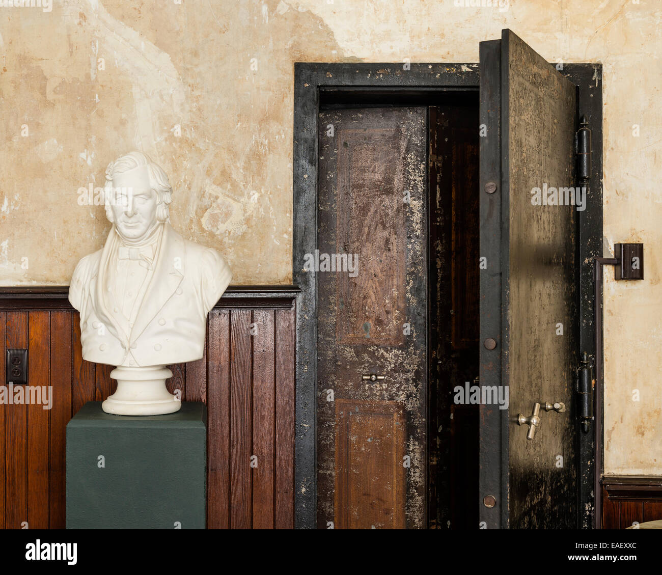 Busto di gesso sul plinto di verde in camera con pannelli in legno e grandi walk-in cassetta di sicurezza Foto Stock