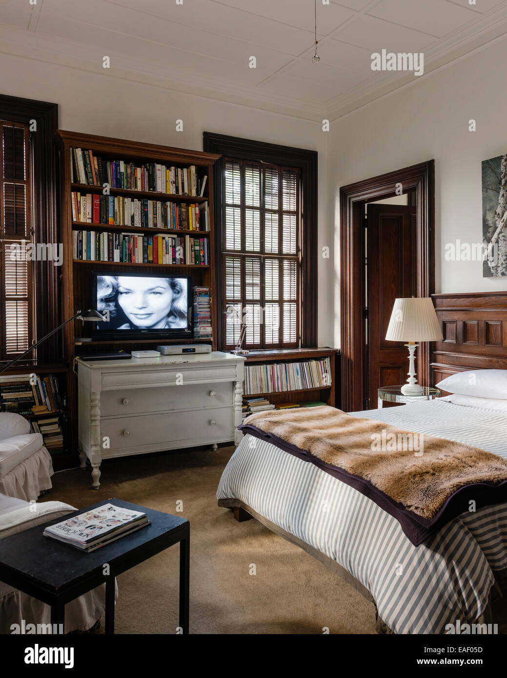 Tv a schermo piatto sopra stile svedese cassettiera in camera da letto con un originale di persiane alle finestre e telai di porte Foto Stock