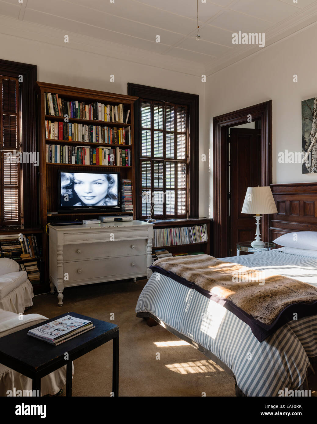 Tv a schermo piatto sopra stile svedese cassettiera in camera da letto con un originale di persiane alle finestre e telai di porte Foto Stock