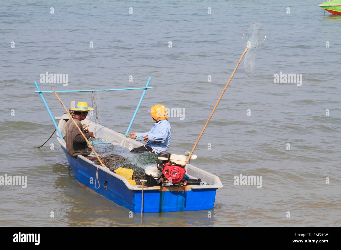 Due fisherman riparazione Tutina in rete nella piccola imbarcazione. Pattaya, Thailandia Foto Stock