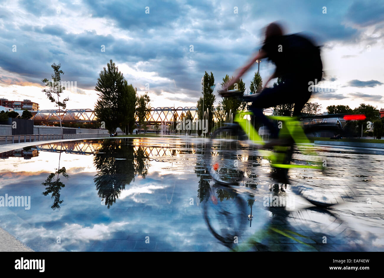Ciclista passando per le piscine e fontane in Madrid Rio Park. Madrid. Spagna Foto Stock