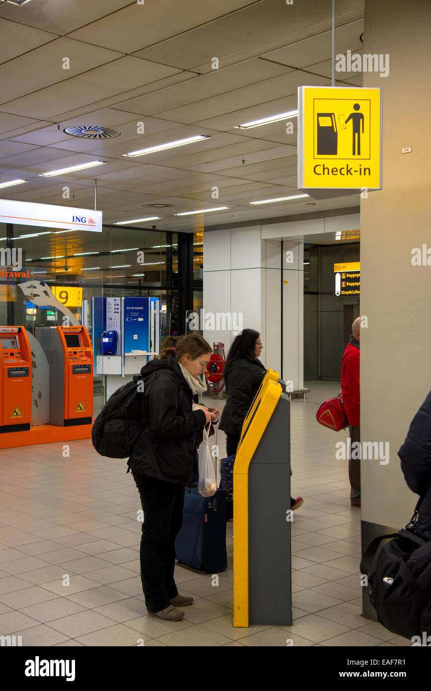 I viaggiatori in automatico di check-in presso l'aeroporto di Schiphol di Amsterdam Olanda Foto Stock