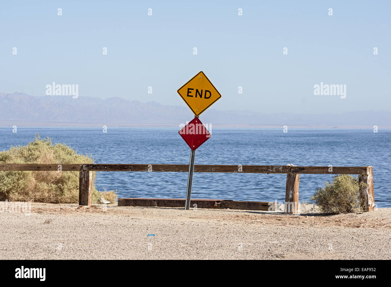 Alla fine della strada dove una strada morti termina nel Salton Sea con un segno e una barriera Foto Stock