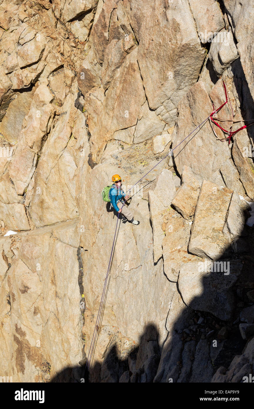 Donna alpinista rappelling giù una scogliera di montagna Foto Stock