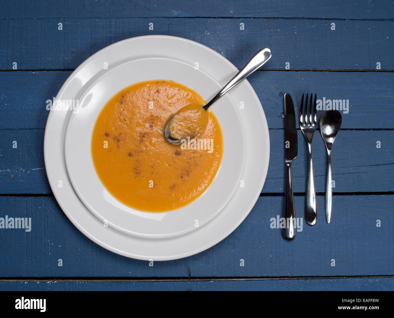 Piatto di zuppa di zucca su un blu tavolo in legno Foto Stock