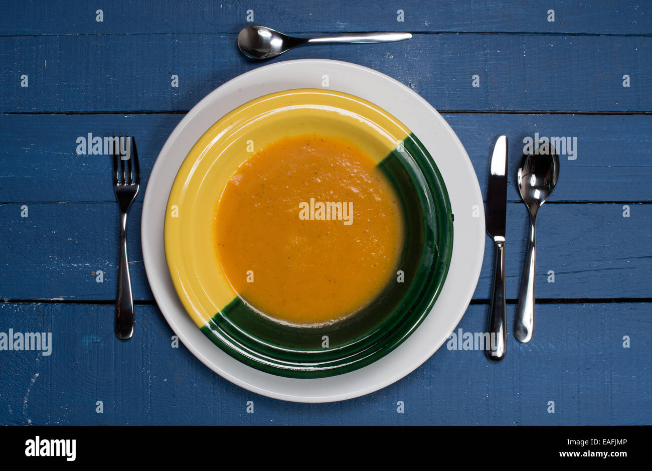 Piatto di zuppa di zucca su un blu tavolo in legno Foto Stock