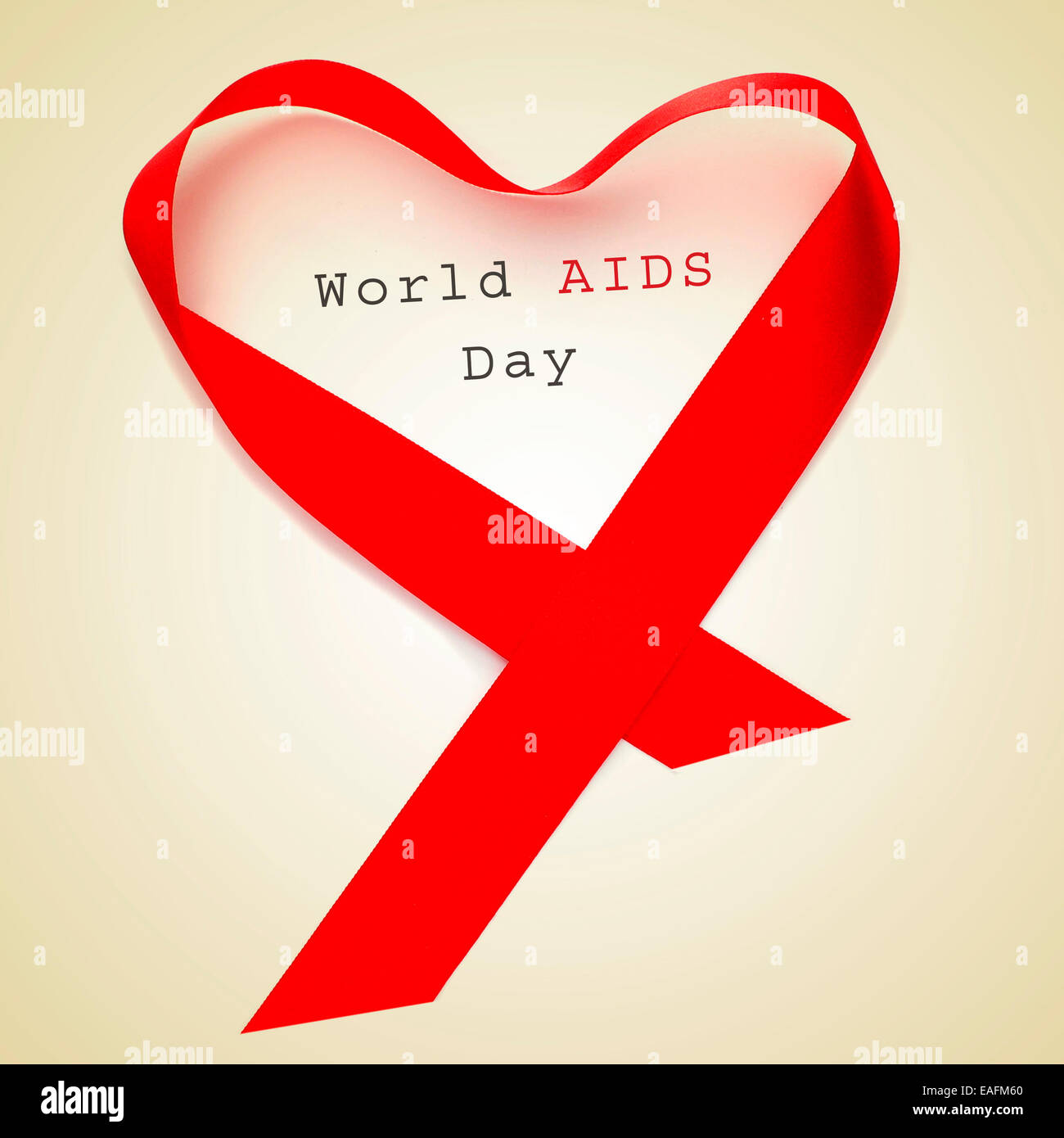 Un nastro rosso formando un cuore e il testo GIORNATA MONDIALE DELL AIDS su uno sfondo beige Foto Stock