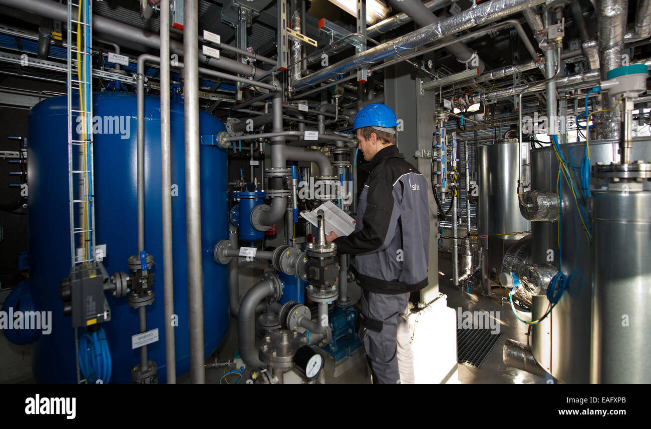 Engineer per le energie rinnovabili e le tecnologie ambientali e dipendente di Sunfire GmbH, Bosse Schluz, illustra le funzioni di un reattore di conversione (blu) durante un press tour presso il Sunfire GmbH stabilimento di Dresda, Germania, 14 novembre 2014. Dresda-basato Sunfire vuole effettuare una sostituzione di petrolio al di fuori dell'acqua e biossido di carbonio con un milione di euro impianto pilota. La potenza al liquido processo converte acqua e biossido di carbonio in un liquido sintetico come carburante benzina, diesel e karosine utilizzando sistemi eco-power. Foto: ARNO BURGI/dpa Foto Stock