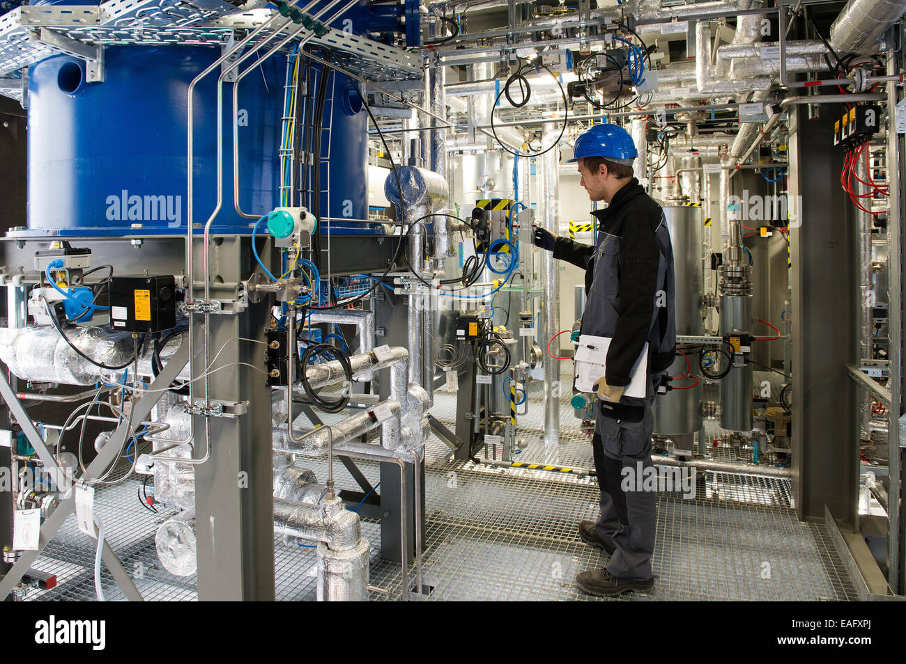 Engineer per le energie rinnovabili e le tecnologie ambientali e dipendente di Sunfire GmbH, Bosse Schluz, illustra le funzioni di un reattore di conversione (blu) durante un press tour presso il Sunfire GmbH stabilimento di Dresda, Germania, 14 novembre 2014. Dresda-basato Sunfire vuole effettuare una sostituzione di petrolio al di fuori dell'acqua e biossido di carbonio con un milione di euro impianto pilota. La potenza al liquido processo converte acqua e biossido di carbonio in un liquido sintetico come carburante benzina, diesel e karosine utilizzando sistemi eco-power. Foto: ARNO BURGI/dpa Foto Stock