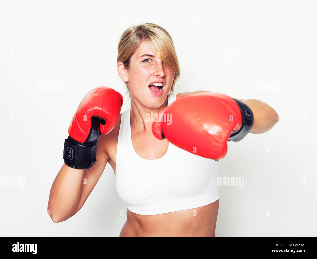 Un giovane sportivo da donna con red guantoni da pugilato, sfondo bianco Foto Stock