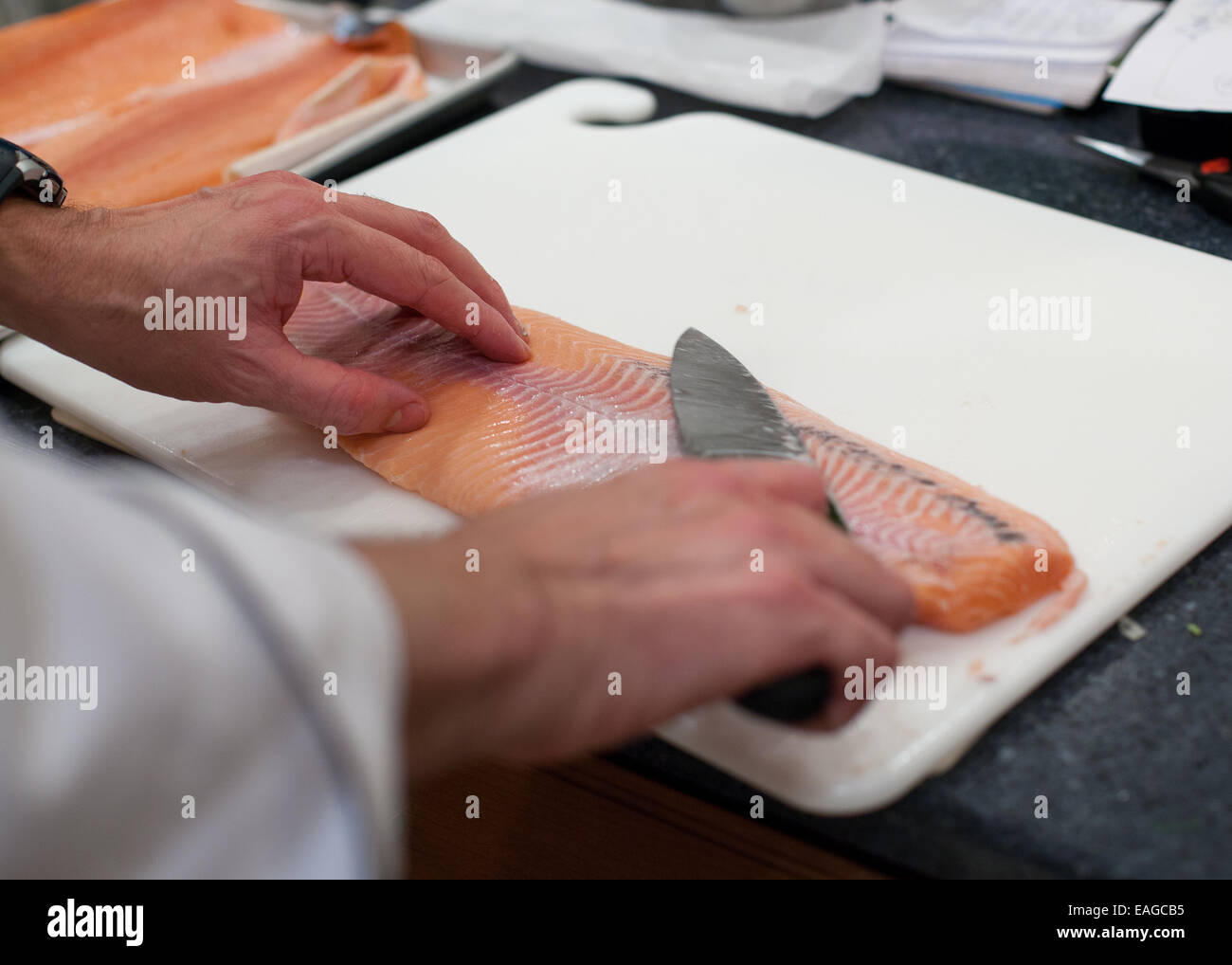 Lo Chef disincrostare un greggio di filetto di salmone con un Coltello per cuoco Foto Stock