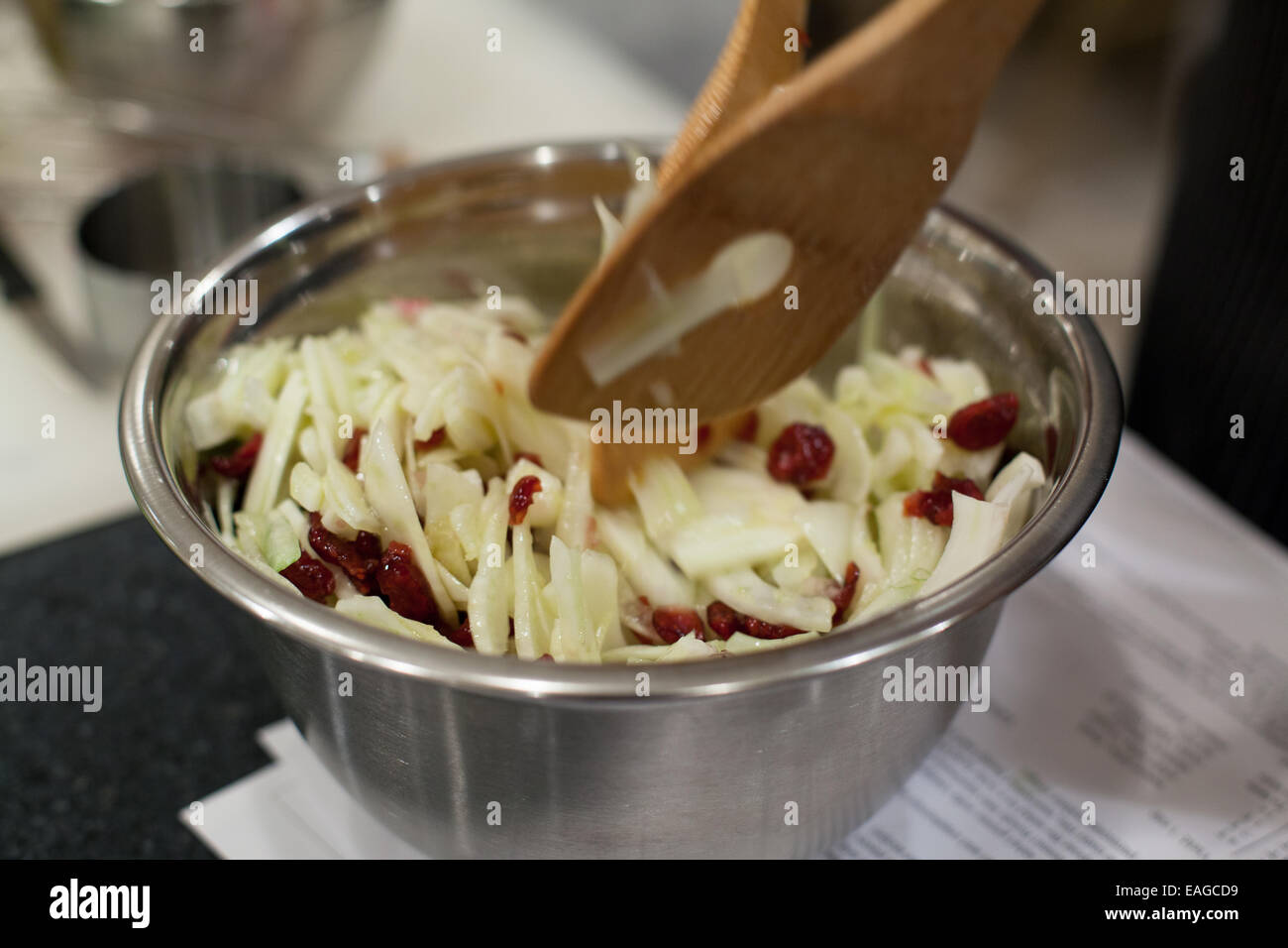 Pinze per insalata mescolando mele, finocchio, e mirtilli rossi per insalata Foto Stock