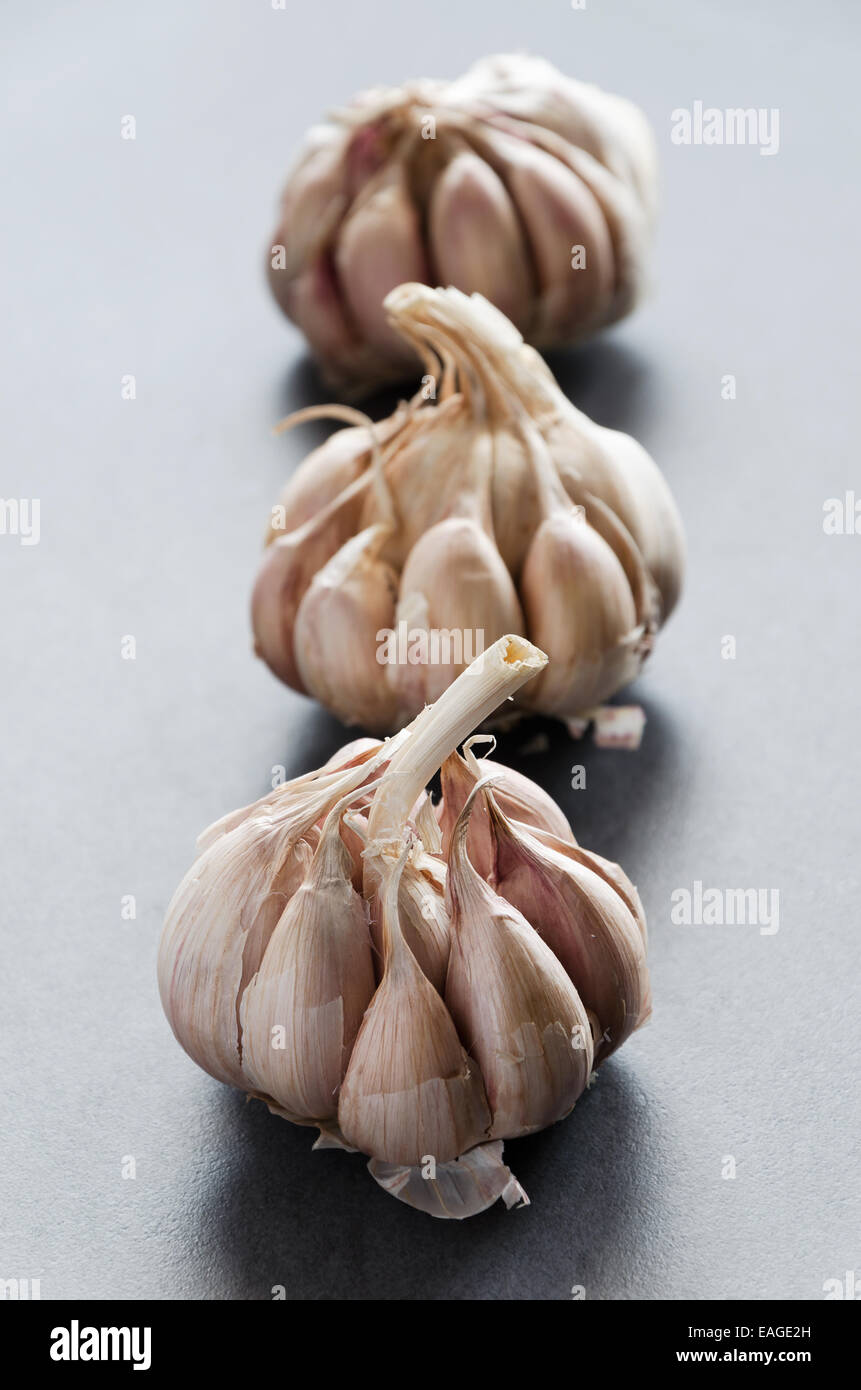 Tre chiodi di garofano di aglio allineati in fila su tavola scuro Foto Stock