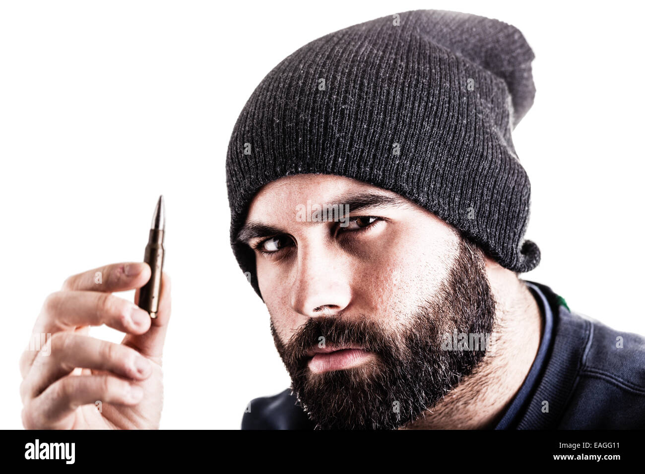 Un uomo barbuto che indossa un beanie hat tenendo un cecchino bullet e lo sta guardando. Isolato su bianco Foto Stock