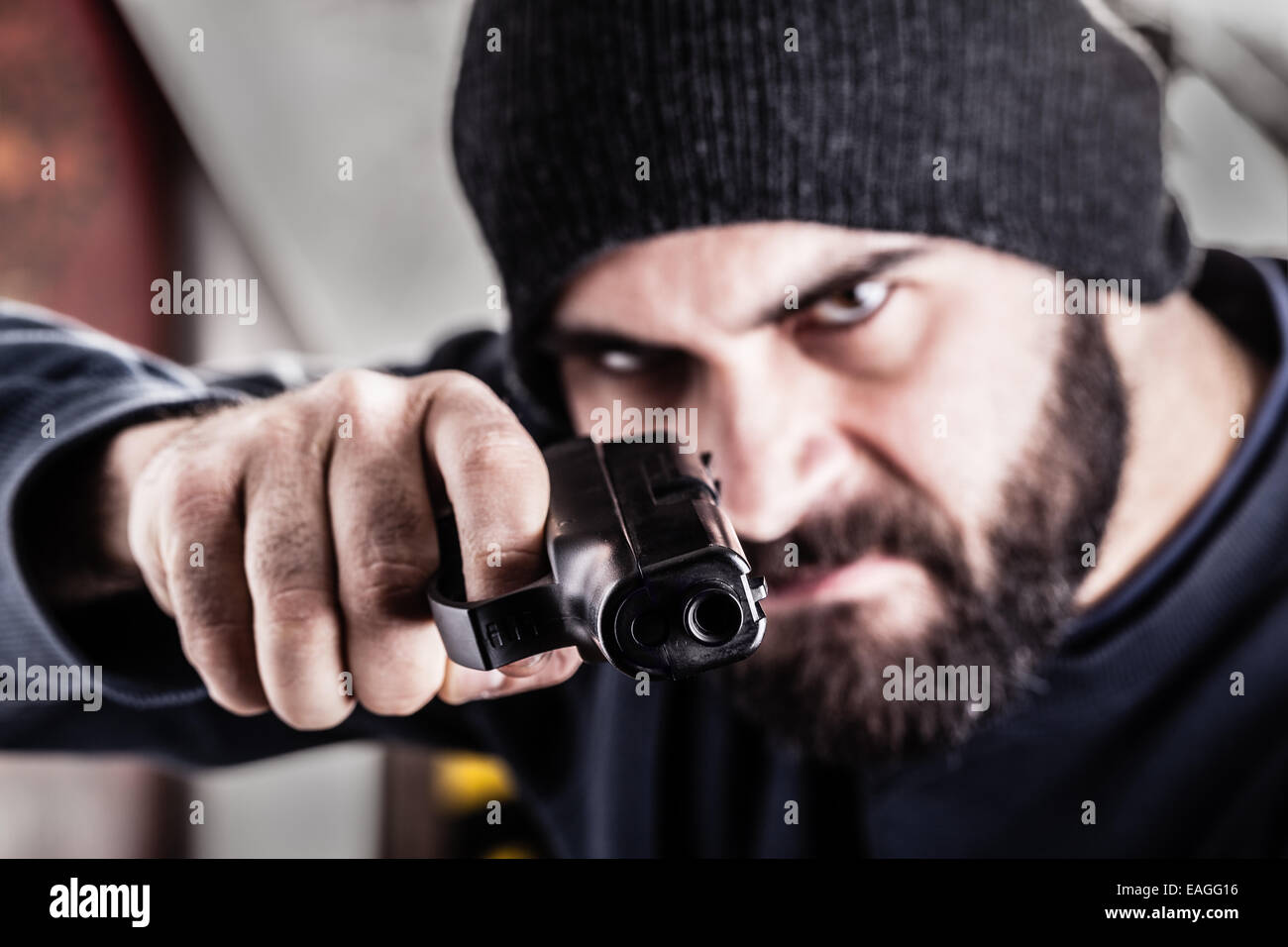 Un barbuto di puntamento penale una pistola e indossando un beanie hat isolato su bianco Foto Stock
