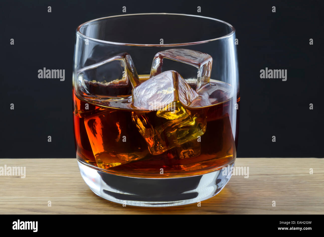 Un grande whisky versata su cubetti di ghiaccio in un semplice vetro Foto Stock