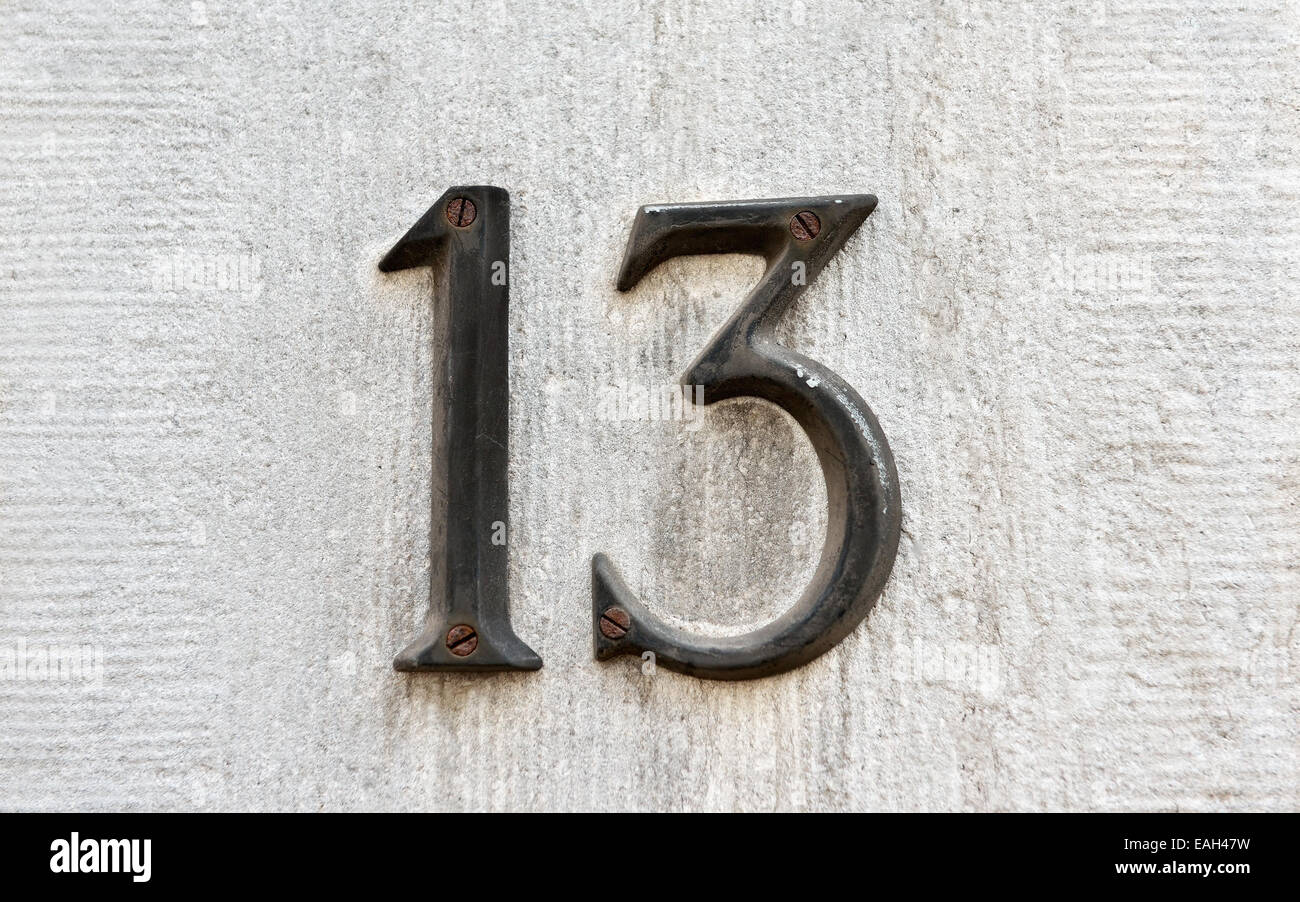 Primo piano immagine di un vecchio metallo arrugginito numero 13 su un muro grigio Foto Stock