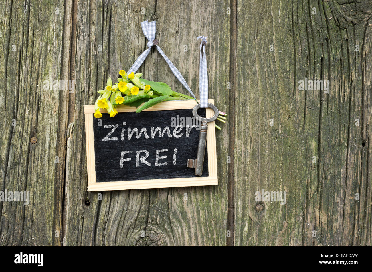 lavagna con chiave, fiori gialli e testo tedesco: stanza in affitto Foto Stock