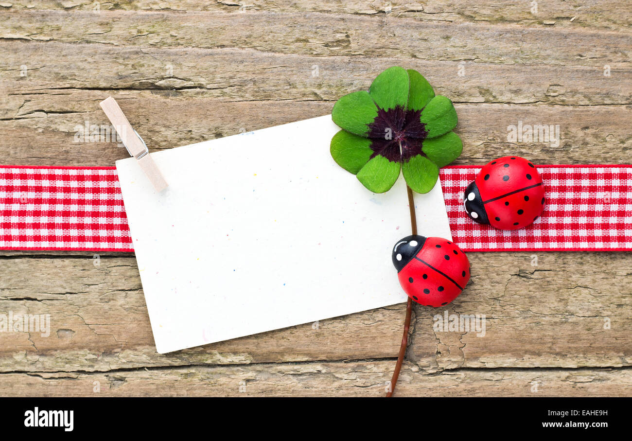 Trifoglio Leafed, ladybugs e carta sul pannello di legno Foto Stock