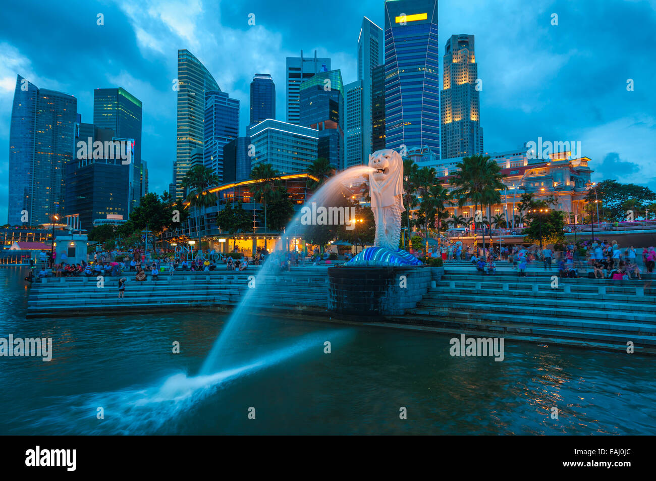 Il Merlion fontana illuminata contro la skyline di Singapore di notte. Foto Stock