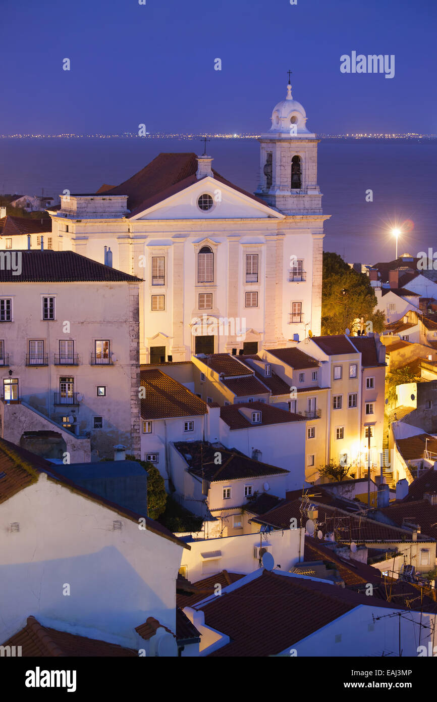 Santo Estevao Chiesa di notte nella città vecchia di Lisbona in Portogallo, fiume Tago in background. Foto Stock