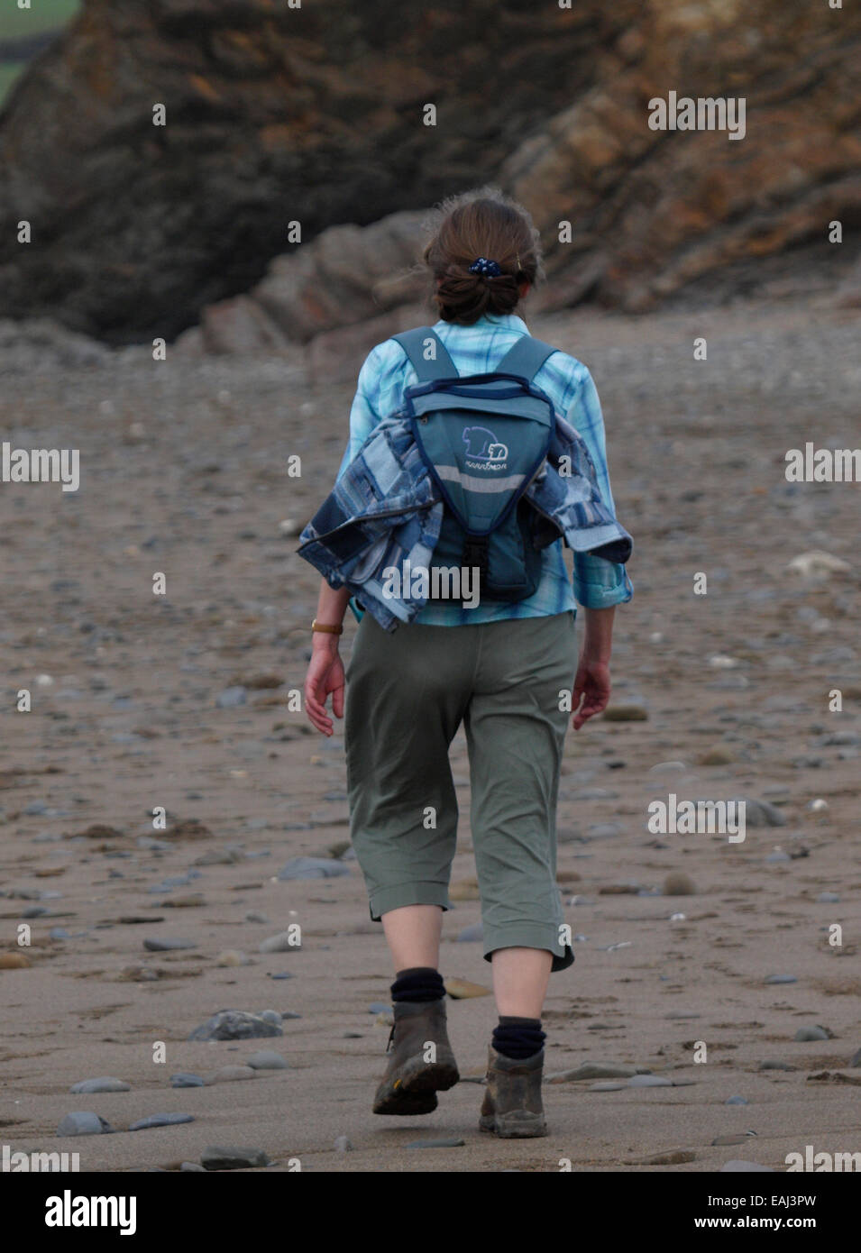 Donna di mezza età escursioni a piedi lungo la spiaggia, Cornwall, Regno Unito Foto Stock
