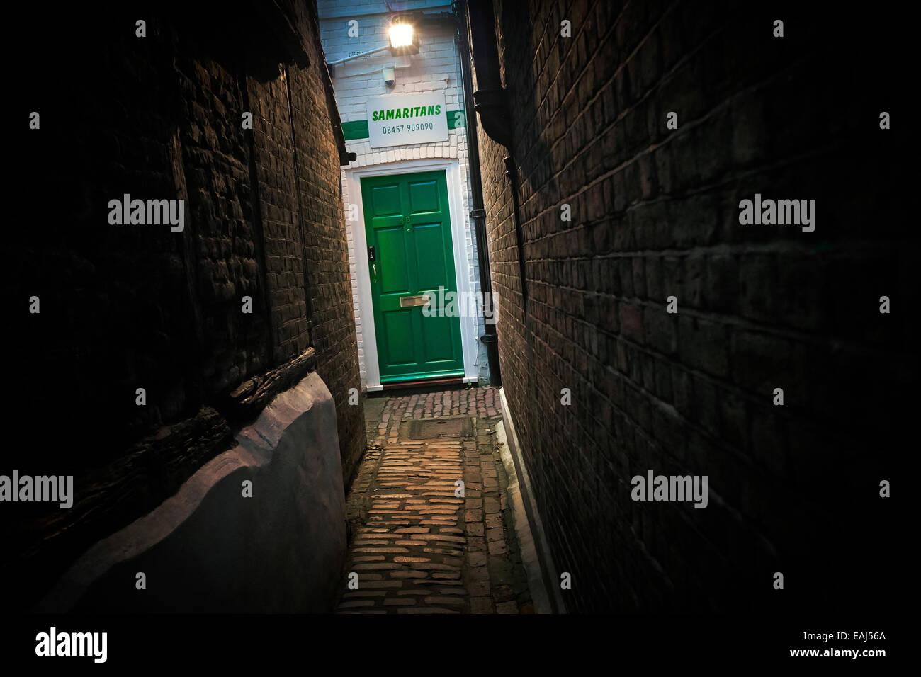 ' La luce alla fine del tunnel ' - Samaritani uffici con segno e porta verde oltre il vicolo. Foto Stock