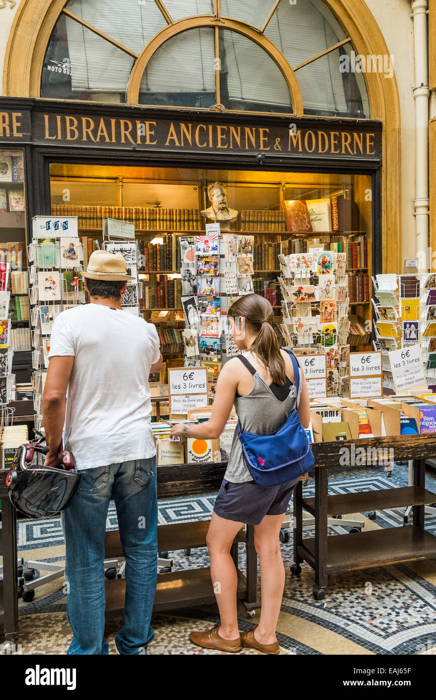 Le persone di fronte a un antiquario bookstore nello storico centro commerciale Galerie Vivienne, Parigi Foto Stock