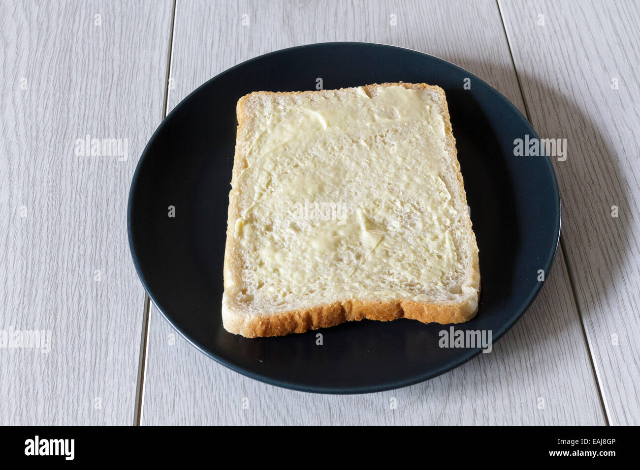 Pezzo di bianco imburrato fette di pane su una piastra Foto Stock