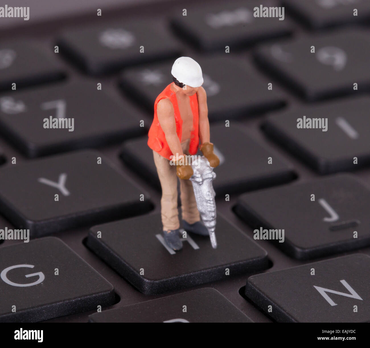 Lavoratore in miniatura con trapano a lavorare sulla tastiera di un computer Foto Stock