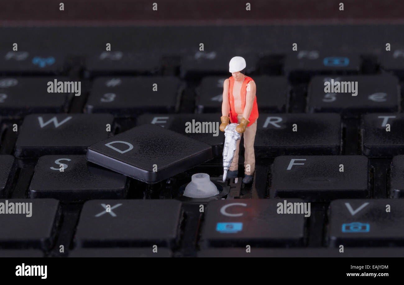 Lavoratore in miniatura con trapano a lavorare sulla tastiera di un computer Foto Stock