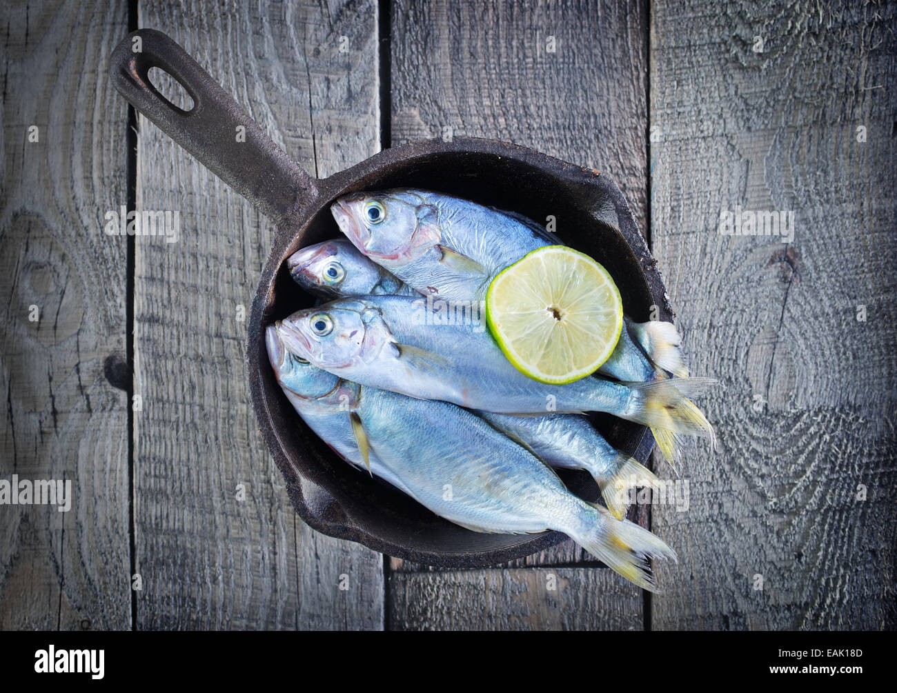 Pesce crudo con limone sul piatto e su un tavolo Foto Stock