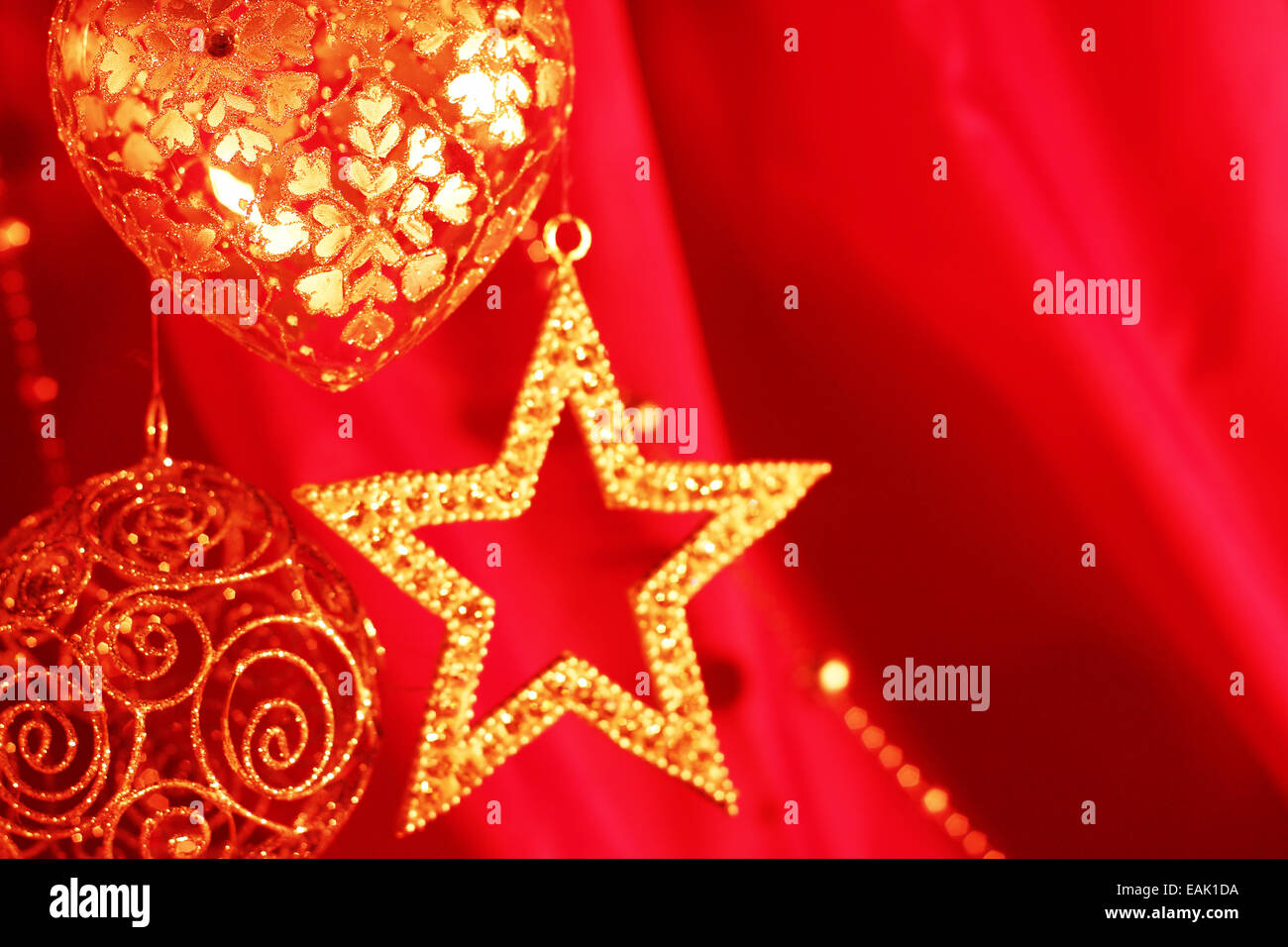 Golden decorazioni di Natale sulla stoffa rossa sullo sfondo Foto Stock